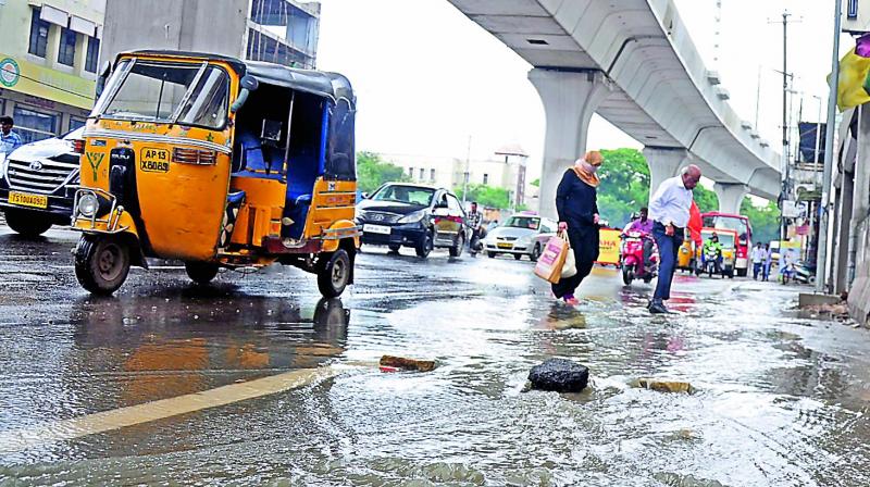 Pedestrians struggle to walk through water overflowing from a drainage at Nampally on Wednesday.  (Photo:DC)