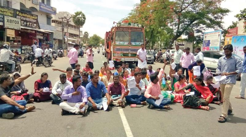 Applicants for the direct recruitment for computer instructor-grade one sit on a dharna, blocking vehicular traffic on the Tiruchengode-Erode highway. (Photo: DC)