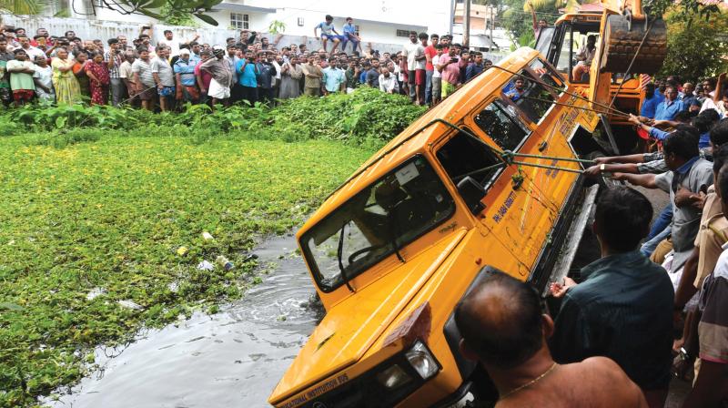 Rescue officials struggle to pull out the play school vehicle that fell into a temple pond at Ayni in Maradu near Kochi on Monday. (Photo: DC)