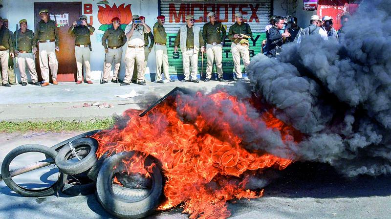 Police personnel look on as tyres are seen ablaze during a strike called by All Assam Students Union and the North East Students Organisation in protest against Citizenship (Amendment) Bill, 2016, in Dibrugarh.  (PTI)