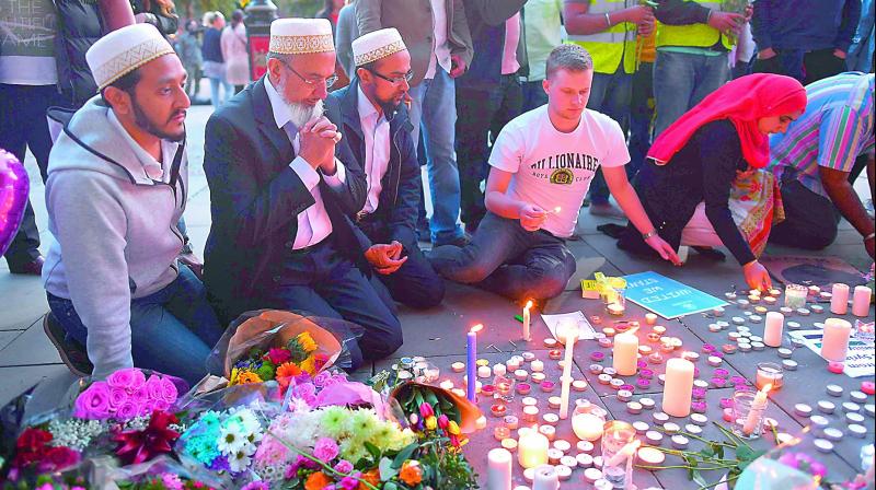 People pray in front of floral tributes in Albert Square in Manchester on Wednesday in solidarity with those killed and injured in the May 23 terror attack at the Ariana Grande concert at the Manchester Arena. (Photo: AFP)