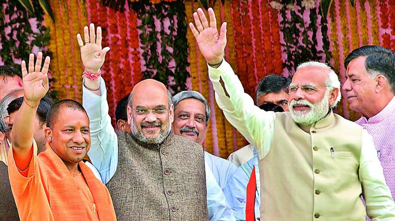 PM Narendra Modi and BJP president Amit Shah wave to the audience along with Yogi Adityanath who was sworn in as UP Chief Minister in Lucknow  on Sunday. (Photo: AP)