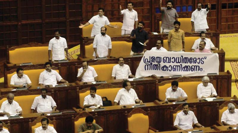Opposition MLAs raise banner demanding justice to victims of floods while the Governors address was in progress in the Assembly on Friday.(A.V. MUZAFAR)