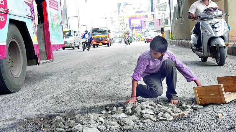 Raviteja a student picks up gravel and stone to fill pot holes under the Habsiguda HMR station. (Photo: Gandhi)