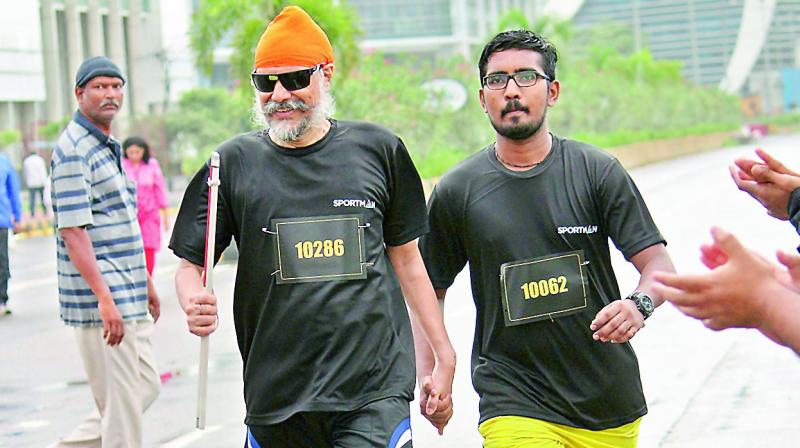 Amarjeet Chawla holds the hand of an escort as he approaches the finish line on one of his runs.