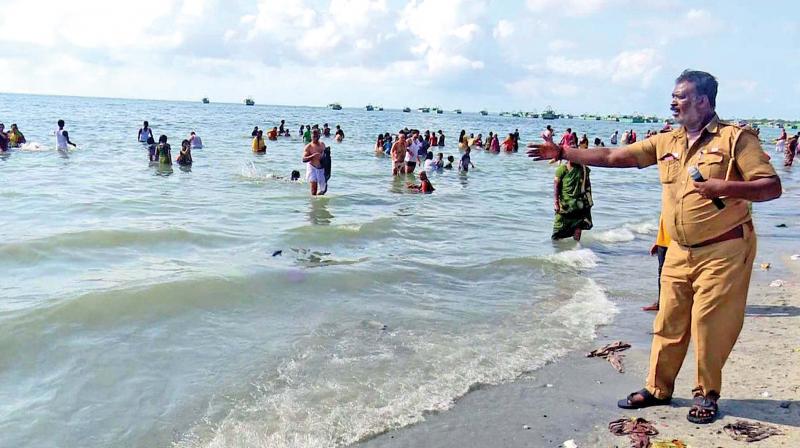 A policeman cautions devotees against taking bath in the sea during  Agnitheertham in Rameswaram on Saturday.  (Photo:DC)
