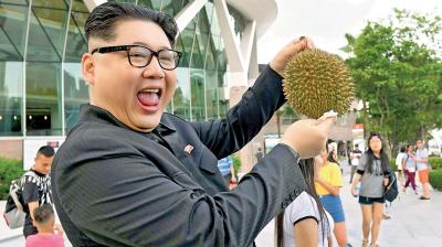  A Kim Jong Un impersonator poses holding a durian fruit in front of the Esplanade theatre in Singapore.