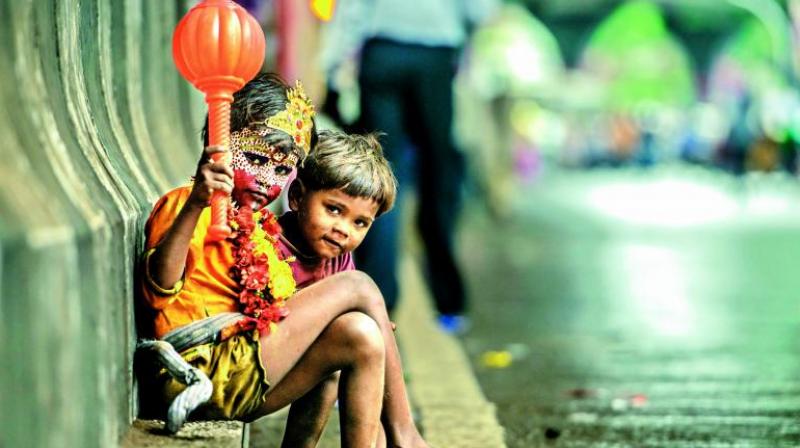 Kids sitting on a road outside a Ganpati pandaal dressed as Gods, expecting money from the devotees.