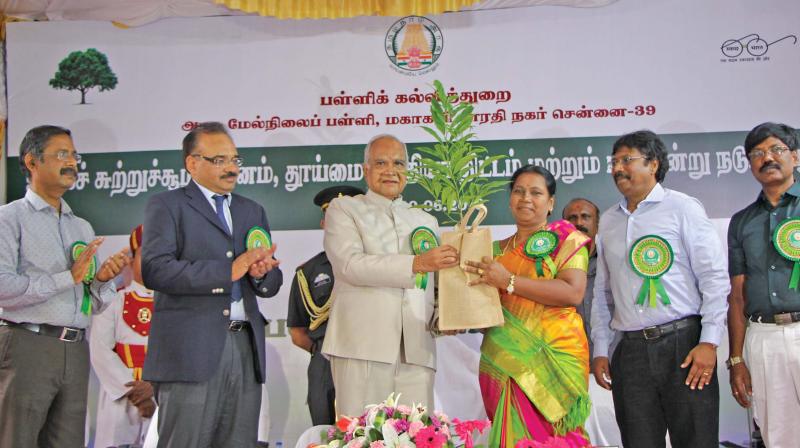 Governor Banwarilal Purohit hands over a sapling to a school teacher on account of Swachh Bharat Abhiyaan and tree plantation day celebrations at government higher secondary school in MKB Nagar in Vyasarpadi on Saturday (Photo: DC)