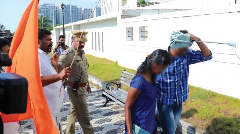A Shiv Sena activist threatens to cane a couple even as Central Station sub-inspector Vijayashankar seems to be pleading with him to spare the duo at Marine Drive in Kochi on Wednesday. (Photo: ARUN CHANDRABOSE)