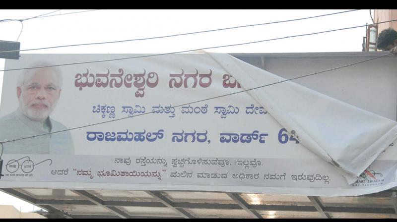 As code of conduct is on, BBMP workers removing a hoarding of MP Sadanandagowda at Rajmahal Nagar in Bengaluru on Saturday   KPN