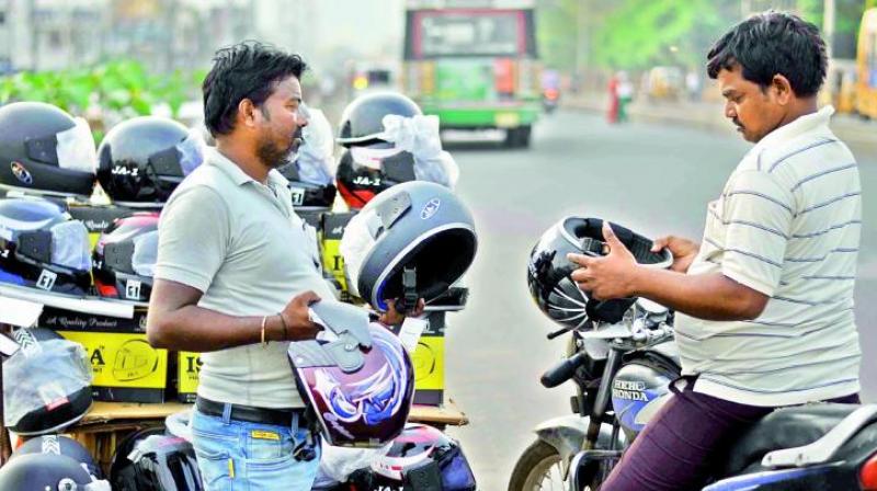 A motorist bargains with a roadside vendor to purchase a helmet  (Photo: DC)