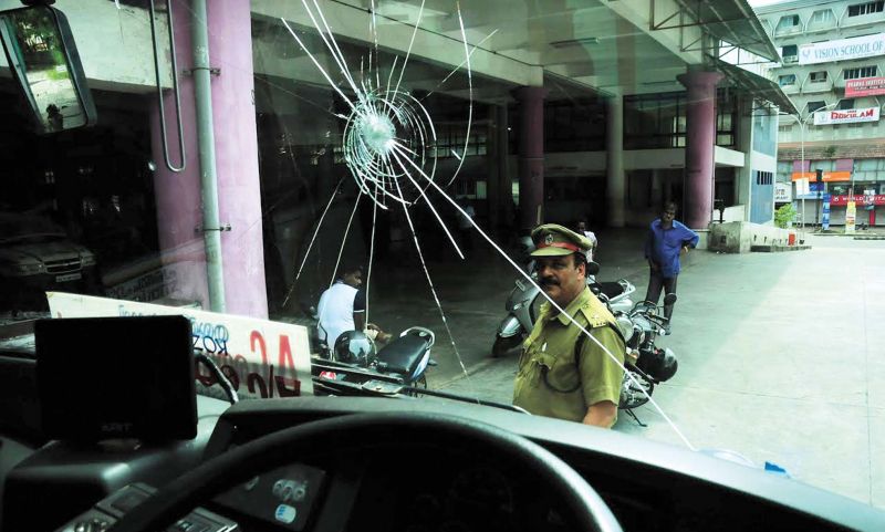 A police official looks at the glass of a KSRTC bus which was destroyed in the stone pelting by anti-socials during the hartal on Thursday. (Photo:  DC)