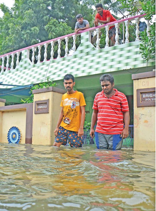 Youngsters of Bharathi Nagar Main Road in West Tambaram come out of their flooded house on Friday. (Photo: DC )