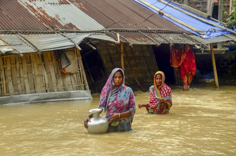 Villagers carry clean water as they wade across flood-affected areas at Nilambazar village, in Karimganj on Sunday. (Photo: PTI)