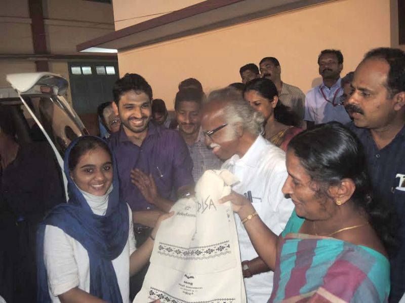 Minister Kadannappally Ramachnadran gifts cloth bag to a student on Friday night. District Collector Mir Mohammed Ali, District Panchayat President KV Sumesh, Mayor E.P Latha among others look on.	(Photo: DC)