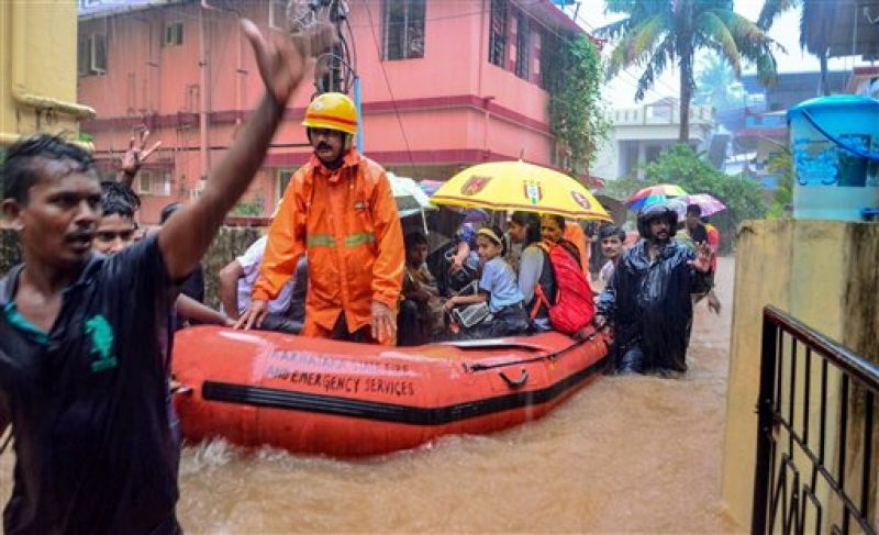 Rescuers shift people to a safer place from a flooded locality, after a thunderstorm, in Mangaluru. (Photo: PTI)