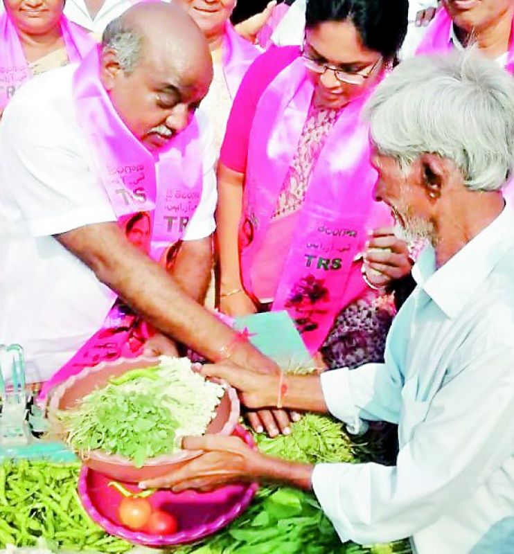 Caretaker minister Jogu Ramanna sells vegetables as part of his campaign in Adilabad on Tuesday. (Photo: DC)