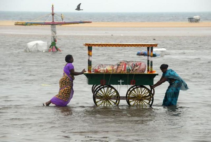  Two women push a food cart through flood waters at Marina Beach on the Bay of Bengal coast, Chennai. (Photo: AFP)