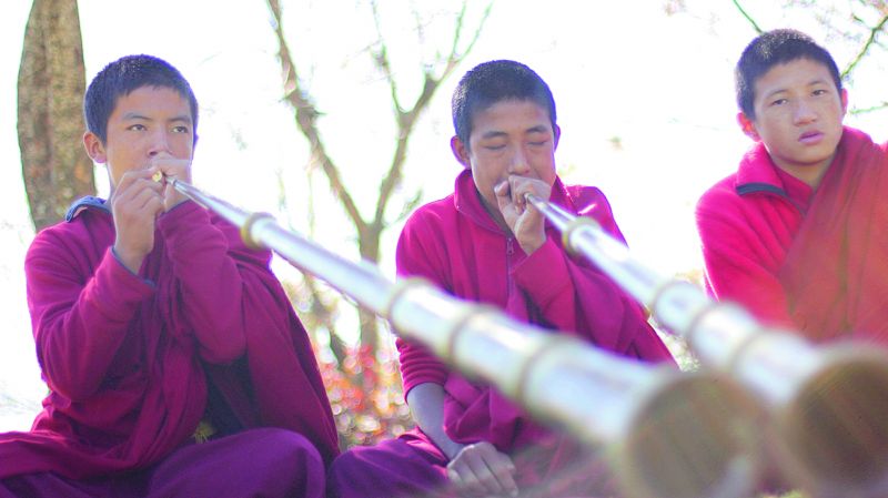 Young monks playing the tung chen at Chimi Lakhang temple