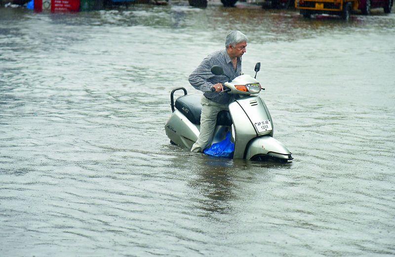 A man struggles with his bike through a waterlogged road in Ranigunj area of the city on Monday. Many roads in the city were flooded which led to traffic blocks. (Photo: DC)