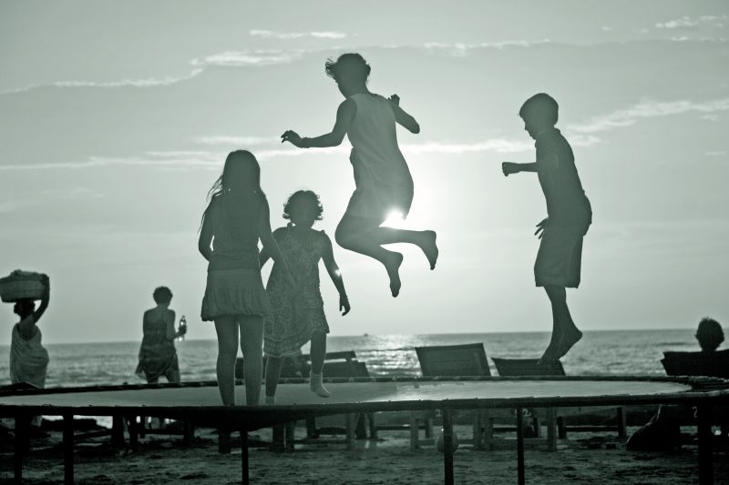 Children leaping with joy in a beach in Goa