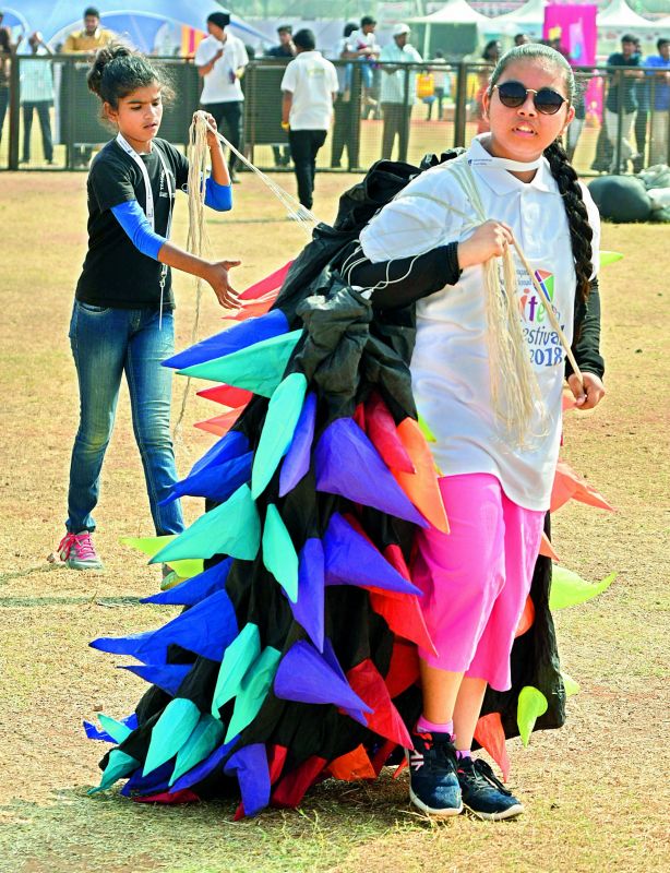 A girl child carries a round kite at the Kite Festival at Parade 