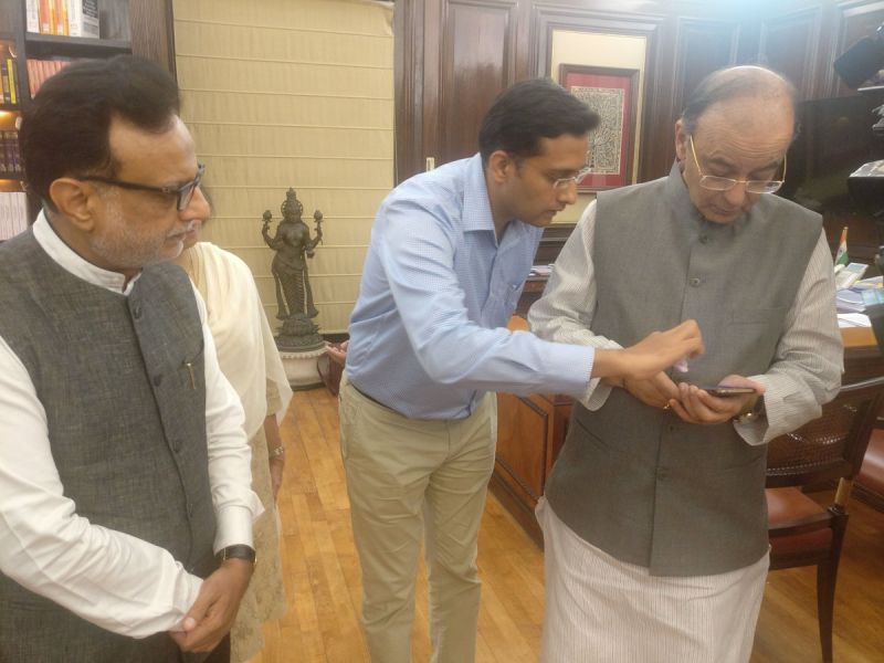 Revenue Secretary Hasmukh Adhia and Finance Minister Arun Jaitley check 'GST Rates Finder' mobile app after its launch.