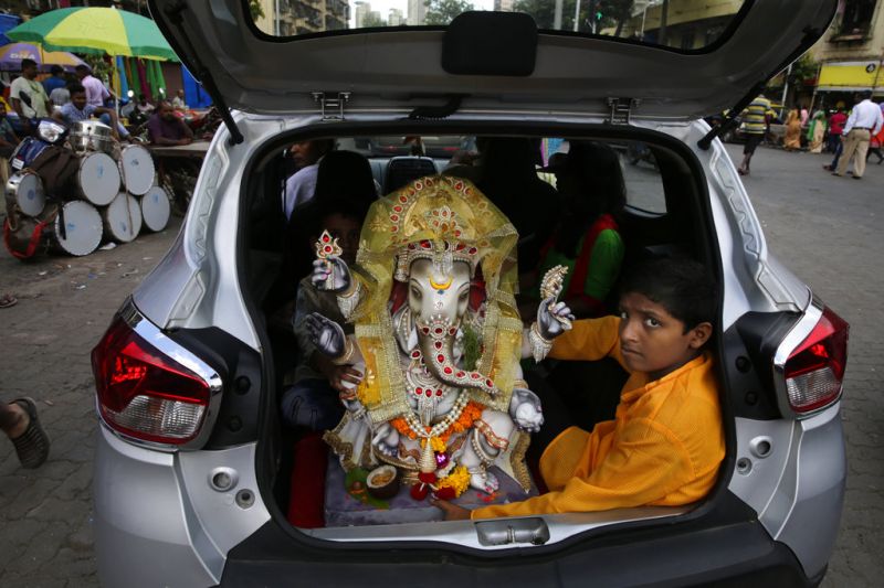 A boy sits with an idol of elephant-headed Hindu god Ganesha in the trunk of a car during Ganesh Chaturthi festival celebrations in Mumbai. (Photo: AP)