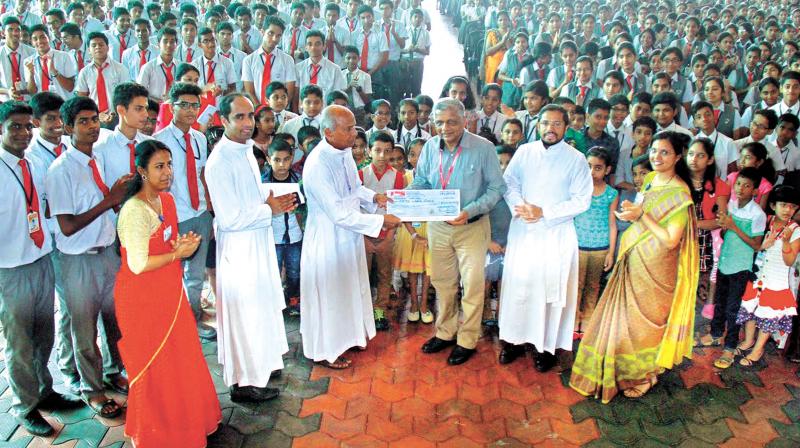 Rajagiri Hospital medical director M.N. Gopinathan Nair receives cheque from school manager Fr. Jose Padayatty.