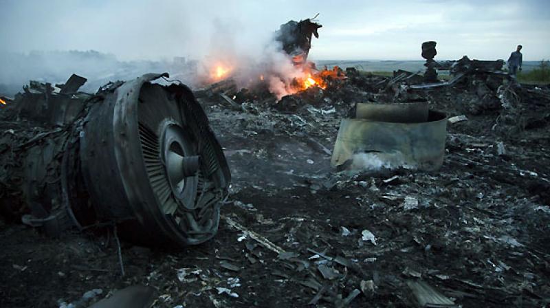 A man walks amongst the debris at the crash site of a passenger plane near the village of Hrabove, Ukraine. (Photo: AP)