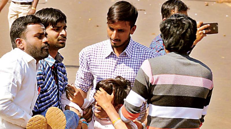 People carry an injured man after police lathicharged members of various organisations protesting against the murder of a girl, Pooja, in Bhalki taluk of Bidar on Tuesday.