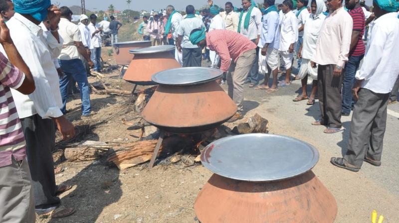 Farmers prepare community meals on the NH-44 at Perkit in Armoor of Nizamabad district, as they stage a protest on seeking higher price for turmeric and red jowar on Saturday. (Photo: DC )
