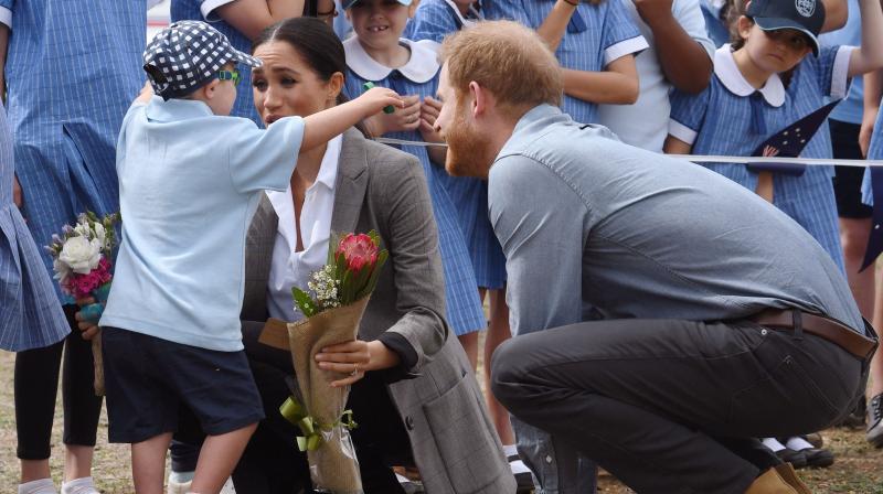 Britains Prince Harry (R) looks on as his wife Meghan, the Duchess of Sussex is hugged by student Luke Vincent of Buninyong Public School following the couples arrival at Dubbo Regional Airport in Dubbo on October 17, 2018. (Photo: AFP)
