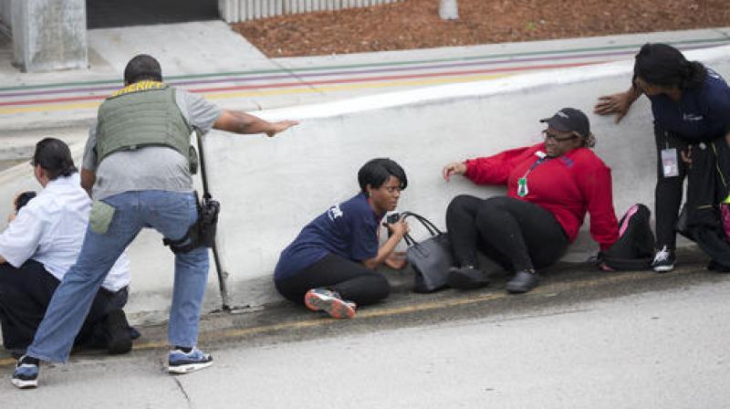 Law enforcement personnel tell people to take cover at Fort LauderdaleHollywood International Airport. (Photo: AP)