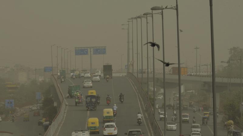 Vehicles ply slowly on a road as dust envelopes the sky over New Delhi, on Wednesday. (Photo: PTI)