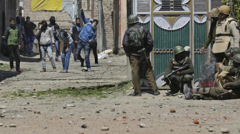 Protesters throw stones on security men outside a poling station during Srinagar by-election. (Photo: AP)
