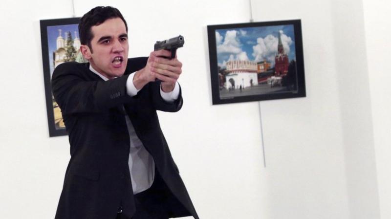 A man identified as Mevlut Mert Altintas holds up a gun after shooting Andrei Karlov, the Russian Ambassador to Turkey, at a photo gallery in Ankara, Turkey on Monday. (Photo: AP)