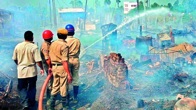Fire service personnel put out the fire that broke out at Konthamuru, where nearly 100 huts were gutted in Rajahmundry on Monday. (Photo: DC)