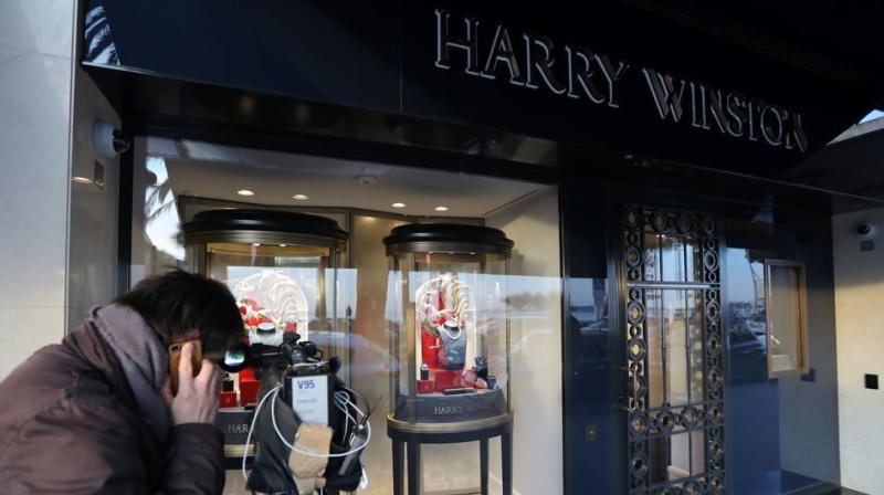 A cameraman films the shop window of the Harry Winston jewelry shop on the Croisette promenade in Cannes, southern France, a few hours after a robbery took place at the shop. (Photo: AFP)