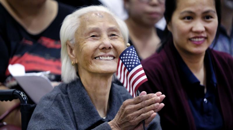 Hong Inh waves an American flag and smiles after taking the oath to become a United States citizen at the Los Angeles Convention Center, Tuesday, Aug. 22, 2017. At 103, the Cambodian woman was the oldest of more than 10,000 people who took the oath of allegiance. Three generations of her family were with her, including her 80-year-old daughter and teenage great-granddaughters. (AP Photo/Richard Vogel)
