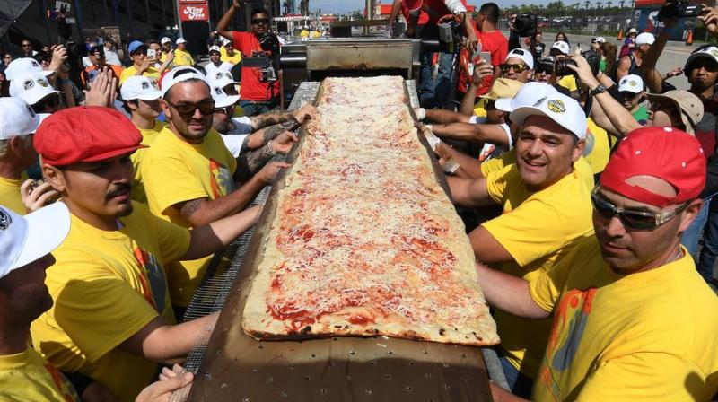 Volunteers feed the final section of the pizza into the mobile oven as they successfully break the Guinness World Record for longest pizza in Fontana, California. (Photo: AFP)