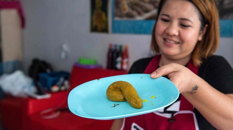 This picture taken on June 19, 2017 shows Wilaiwan Mee-Nguen showing off a dessert in the shape of dog poop that she prepared at her home in Bangkok. (Photo: AFP)