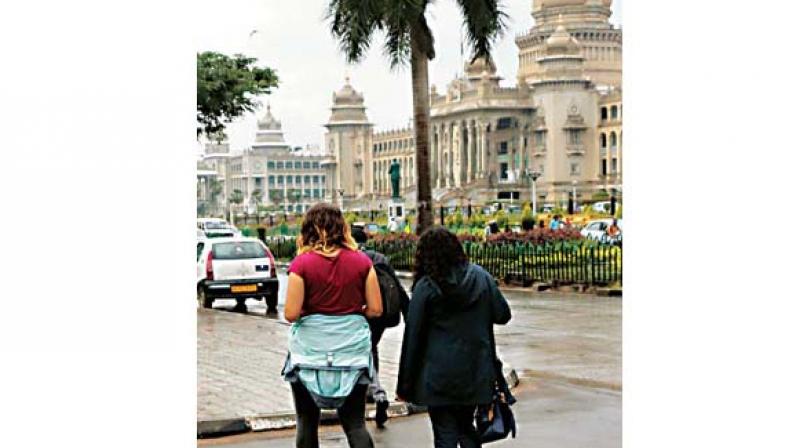 Visitors walk past Vidhana Soudha as Bengaluru receives rain on Friday   Image: KPN