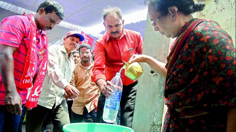 Naga Shiromani, who lives close to the Dharna Chowk, gives drinking water to thirsty activists demanding revival of the Chowk at Indira Park in Hyderabad on Monday. Ms Shiromani said that she never had a problem with the protests at the Dharna Chowk. (Photo: S. Surender Reddy)