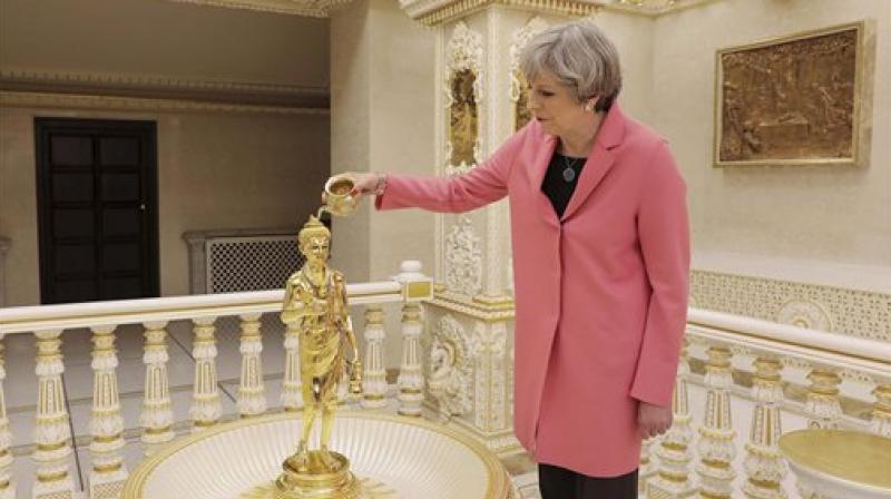 Prime Minister May was accompanied by her husband Philip and both removed their shoes before entering the Swaminarayan temple in north-west London on Saturday. (Photo: PTI)