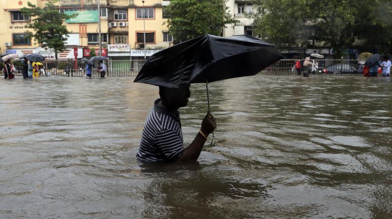 A man wades through a waterlogged street following heavy rains in Mumbai on Tuesday. (Photo: AP)