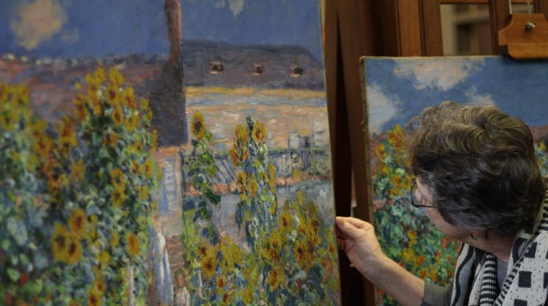 Emily Talbot, assistant curator of the Norton Simon Museum, shines a flashlight on \The Artists Garden at Vetheuil\ (1881) by Claude Monet at the National Gallery of Arts conservation laboratory in Washington on May 17, 2018. (Photo: AFP)