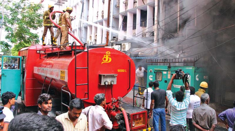 TNFRS personnel in the process of dousing fire at Dass India Towers in Second Line Beach Road, Parrys, on Friday. (Photo: DC)