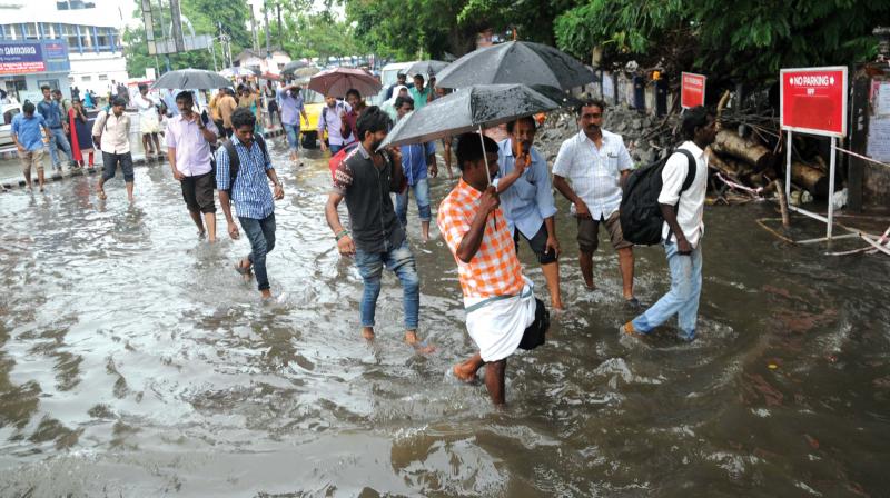 Commuters coming out the Ernakulam South railway station wade through water-logged road as autorickshaws and taxis refused to ply after the heavy rains on Monday. (Photo: Arunchandra Bose)